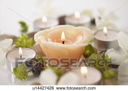 Stock Photo - Burning candles and stones, close up, white background. Fotosearch