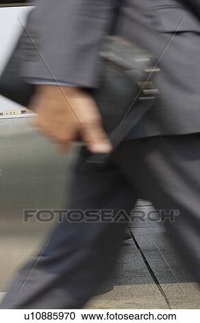 Businessman walking, holding a bag, blurred motion View Large Photo Image Stock Image - Businessman walking, holding a bag, blurred motion. Fotosearch