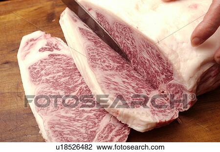 Stock Image - Chef cutting meat, close up. Fotosearch