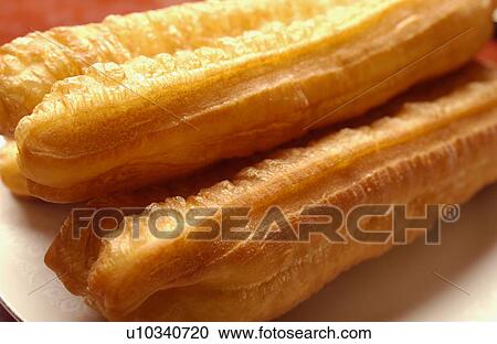 Stock Image - Chinese fried bread sticks on plate, close up. Fotosearch