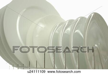 Stock Photo - Clean plates on dish rack, close up, white background. Fotosearch
