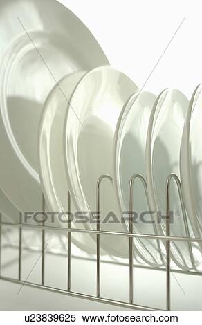 Stock Photography - Clean plates on dish rack, close up, white background. Fotosearch