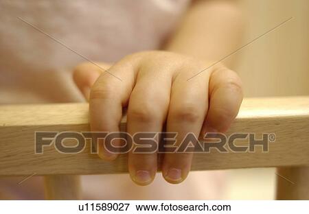 Close-up of baby girl holding crib View Large Photo Image Stock Photo - Close-up of baby girl holding crib. Fotosearch