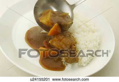 Stock Image - Curry being poured on plate of rice, white background. Fotosearch