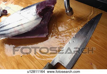 Picture - Cut bonito and kitchen knife on cutting board. Fotosearch