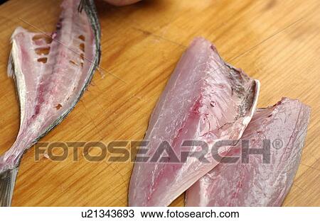 Stock Image - Cut horse mackerel on cutting board, close up. Fotosearch