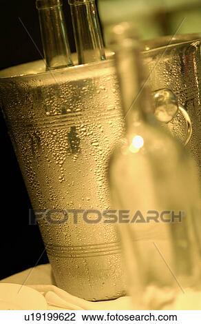 Stock Image - Empty wine bottle and ice bucket, close up. Fotosearch