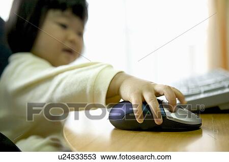 Stock Image - Girl using computer, holding computer mouse, smiling. Fotosearch