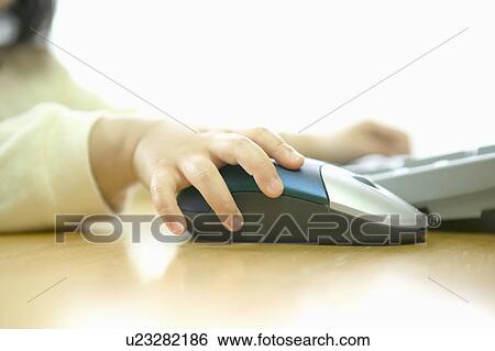 Stock Photograph - Girl using computer, holding computer mouse. Fotosearch