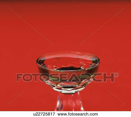 Stock Photo - Glass of Sake, close up, red background. Fotosearch
