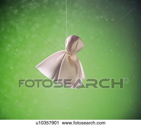 Stock Image - Hanged doll made of white cloth, green background. Fotosearch