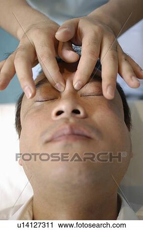 Stock Image - Man getting Shiatsu on his face. Fotosearch