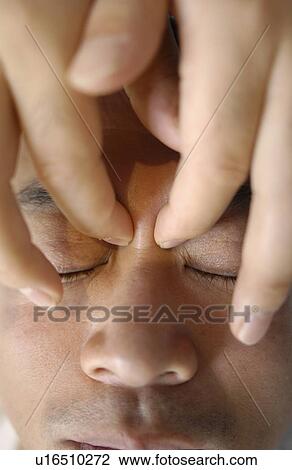 Stock Image - Man getting Shiatsu on his face. Fotosearch