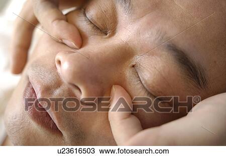 Stock Image - Man getting Shiatsu on his face. Fotosearch