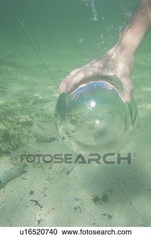 Man holding a glass globe in the water View Large Photo Image Stock Image - Man holding a glass globe in the water. Fotosearch