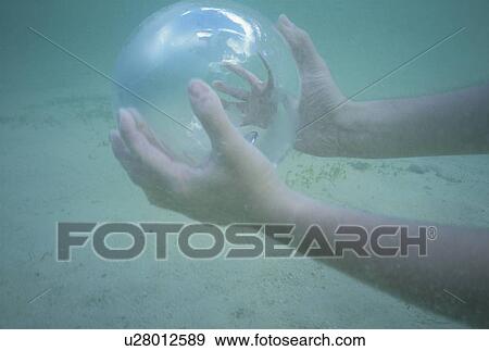 Stock Photo - Man holding a glass globe in the water. Fotosearch