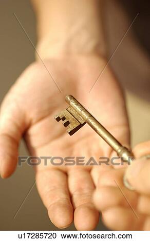 Stock Image - Man receiving a rusted key, close up. Fotosearch