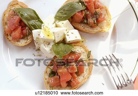 Stock Image - Mozzarella cheese and tomato on bruschetta. Fotosearch