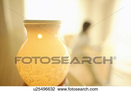 Oil lamp, woman sitting at table in background, differential focus View Large Photo Image Stock Image - Oil lamp, woman sitting at table in background, differential focus. Fotosearch