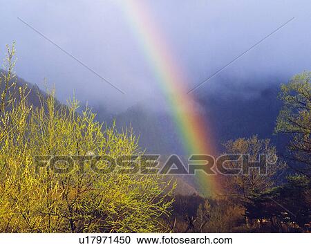 Stock Image - Rainbow between mountain ranges. Fotosearch