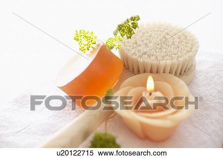 Stock Photography - Soap, candle and back brush on white towel, white background. Fotosearch