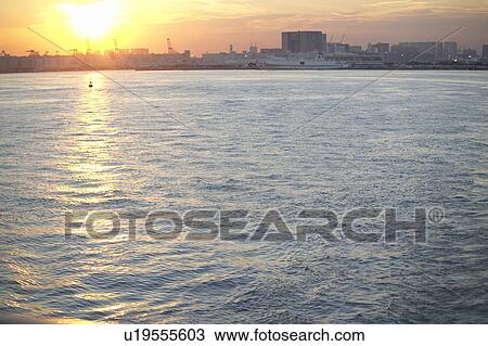 Stock Image - Sunset Over the Sea, Buildings in Background. Fotosearch