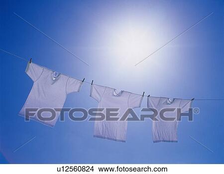 Three T-shirts being hanged out under blue sky, blue background View Large Photo Image Picture - Three T-shirts being hanged out under blue sky, blue background. Fotosearch