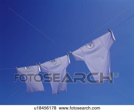 Three T-shirts being hanged out under blue sky, blue background View Large Photo Image Stock Photo - Three T-shirts being hanged out under blue sky, blue background. Fotosearch