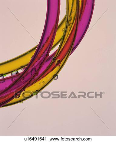 Stock Image - Water drops on garden hose, close up, colored background. Fotosearch
