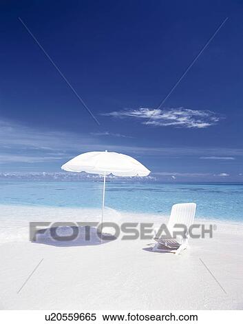 Stock Photography - White deck chair and parasol on beach. Fotosearch