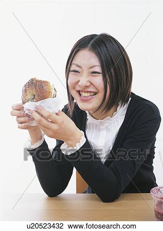 Young woman holding a bagel, smiling, white background View Large Photo Image Stock Image - Young woman holding a bagel, smiling, white background. Fotosearch