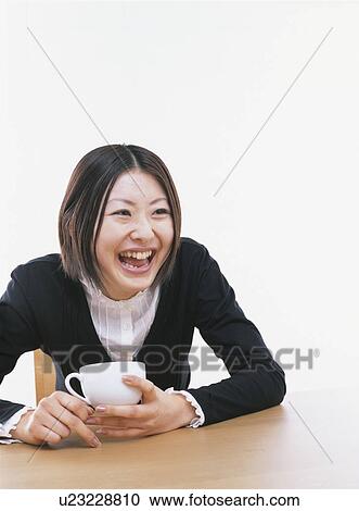 Stock Image - Young woman holding a coffee cup, smiling, white background. Fotosearch