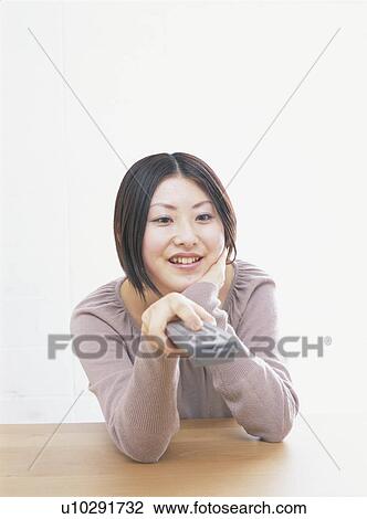 Young woman holding remote control, smiling, white background View Large Photo Image Stock Image - Young woman holding remote control, smiling, white background. Fotosearch