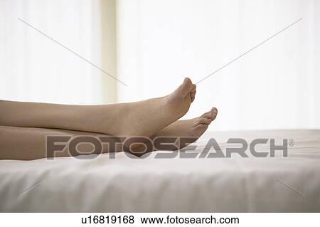 Stock Photo - Young woman lying on bed. Fotosearch
