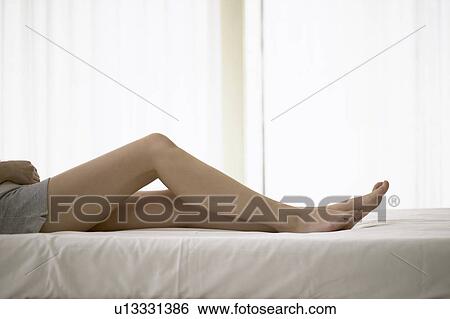 Stock Photograph - Young woman lying on bed. Fotosearch
