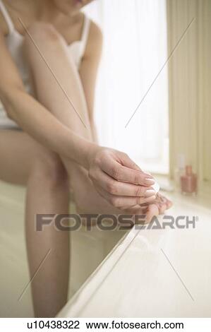 Stock Image - Young woman polishing toenails. Fotosearch