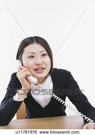 Stock Photograph - Young woman using phone, white background. Fotosearch