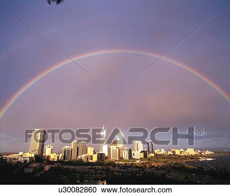 Stock Image - Rainbow over city skyline, Australia. Fotosearch