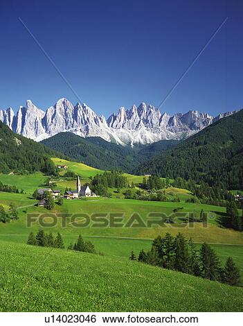 Stock Photograph - Small village and farmland in front of Geisler Gruppe, Italy. Fotosearch