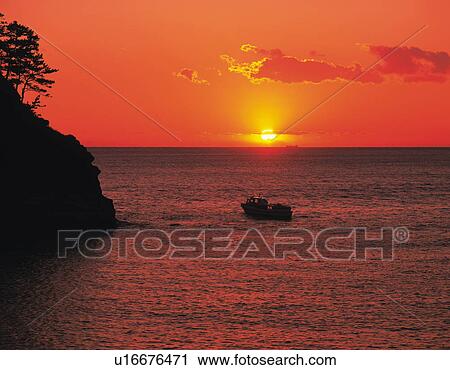 Stock Image - Sun setting over the ocean, Dogashima, Shizuoka Prefecture, Japan. Fotosearch