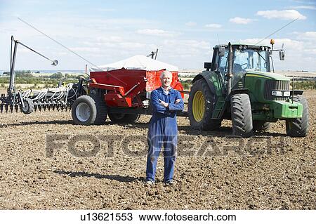 Stock Image - Driver Standing In Front Of Tractor. Fotosearch