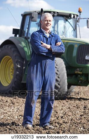 Stock Image - Driver Standing In Front Of Tractor. Fotosearch