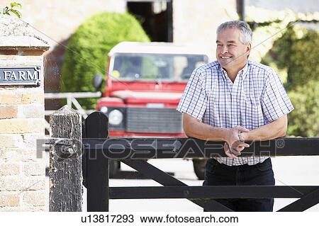 Stock Image - Farmer Looking Over Farm Gate. Fotosearch