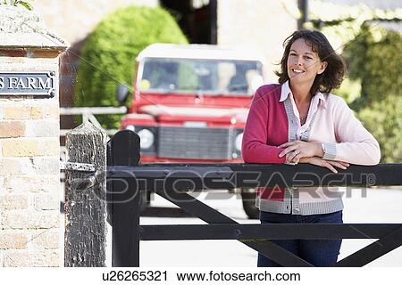 Stock Image - Farmer's Wife Looking Over Farm Gate. Fotosearch
