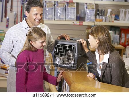 Stock Image - Girl And Father Taking Cat For Examination By Vet. Fotosearch