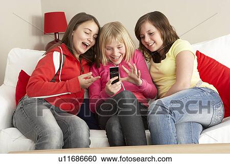 Stock Image - Group Of Three Girls Reading Text Message. Fotosearch