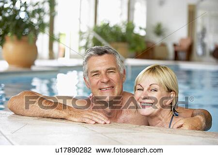 Stock Image - Middle Aged Couple In Swimming Pool. Fotosearch