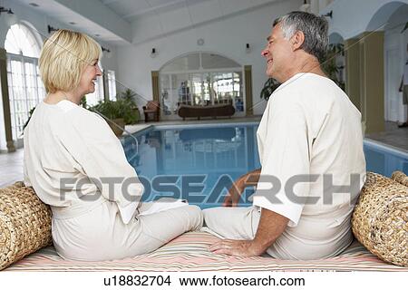 Picture - Middle Aged Couple Relaxing By Swimming Pool. Fotosearch