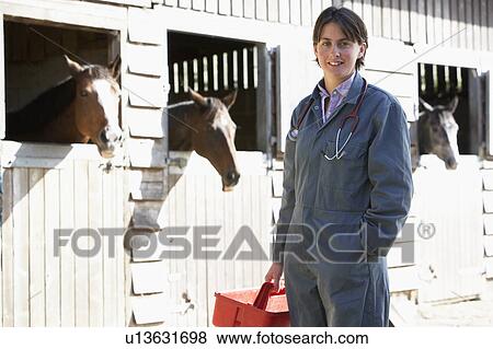 Stock Photo - Portrait Of Vet Standing By Horse Stables. Fotosearch