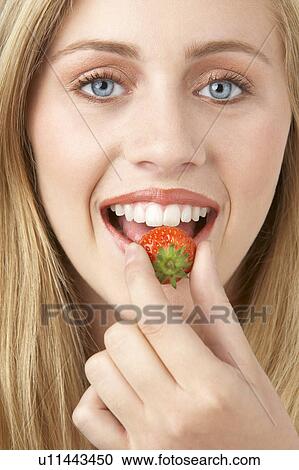 Stock Image - Portrait Of Young Woman Eating Strawberry. Fotosearch